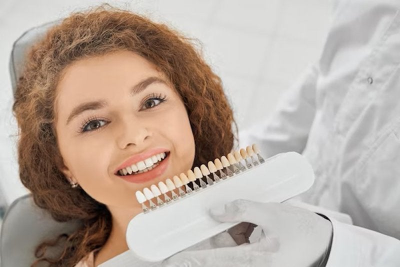 Mujer recostada sonriendo y con un medido de tono de dientes